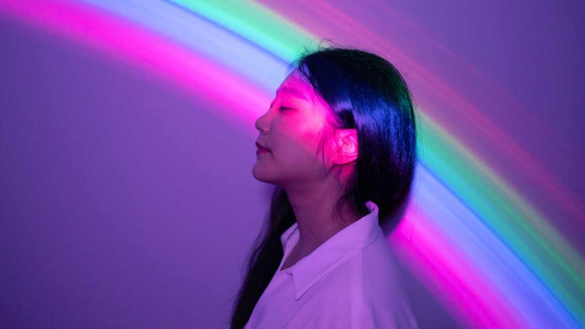 Frau vor lila Wand mit Regenbogenlicht
