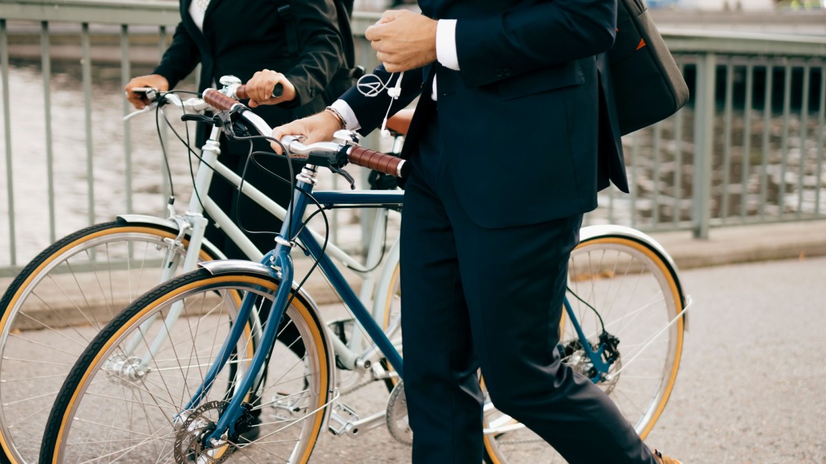 Zwei Männer im Anzug schieben ihre Fahrräder