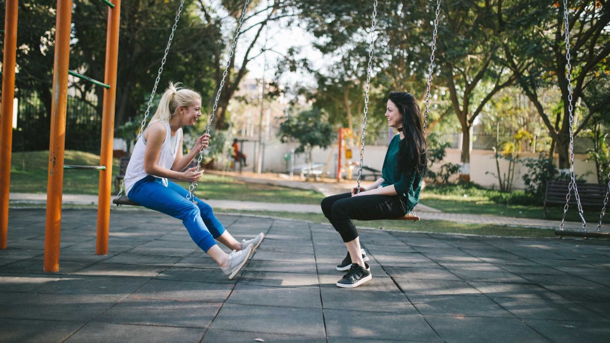 zwei Frauen unterhalten sich auf einer Spielplatz-Schaukel