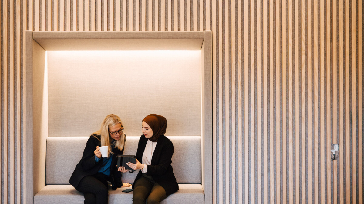 Zwei Frauen unterhalten sich in einer modernen Büro-Siitzecke
