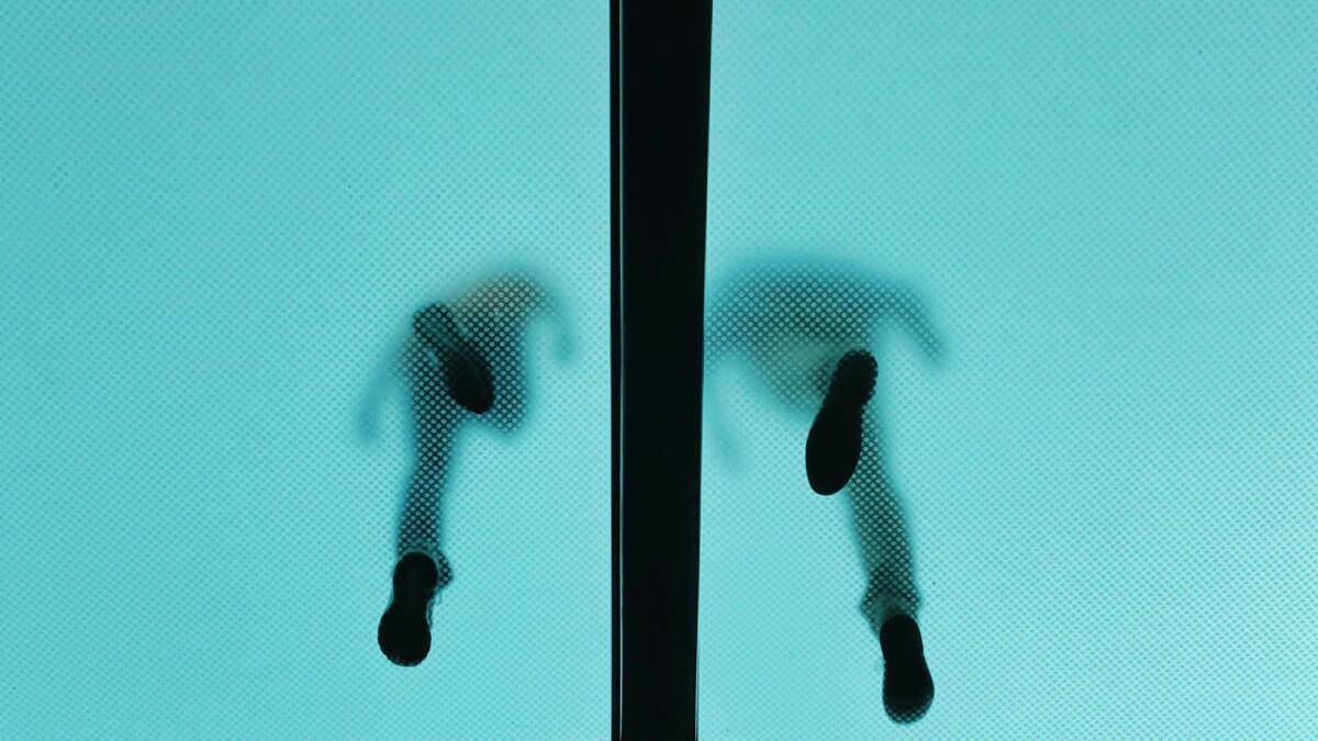 zwei Menschen laufen auf einer Milchglasscheibe (Froschperspektive)
