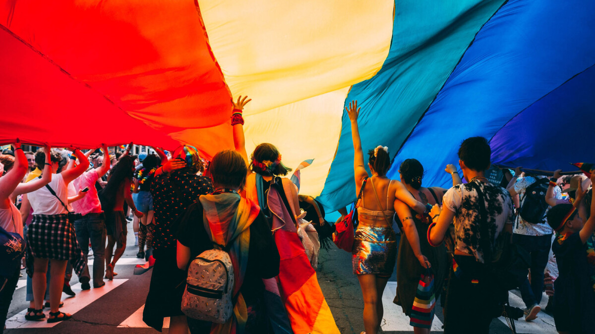 Menschen laufen unter einer Regenbogenflagge